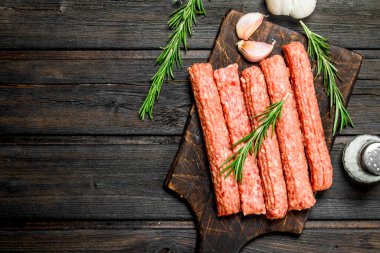 Baharat ve otlar ile çiğ Dana sosis. Ahşap bir arka plan üzerinde.