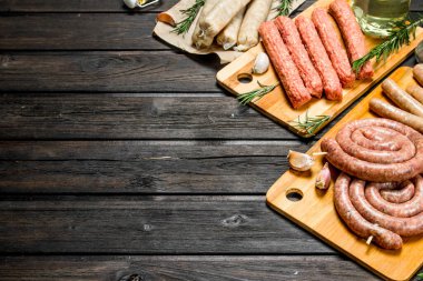 Baharat ile ahşap tahta üzerinde çiğ sosis çeşitleri. Ahşap bir arka plan üzerinde.