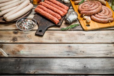 Baharat ve otlar ile çiğ sosis farklı türleri. Ahşap bir arka plan üzerinde.