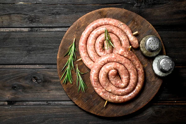 stock image Raw sausages with herbs on a wooden Board. On a wooden background.