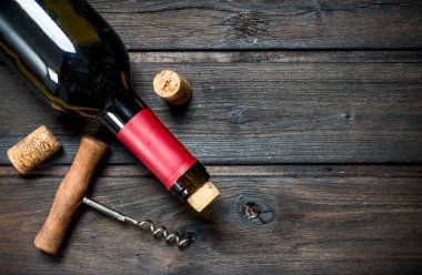 kırmızı şarap ile bir tirbuşon bir şişe. Ahşap bir arka plan üzerinde.