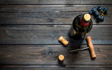 bir şişe kırmızı şarap üzüm ile. Ahşap bir arka plan üzerinde.