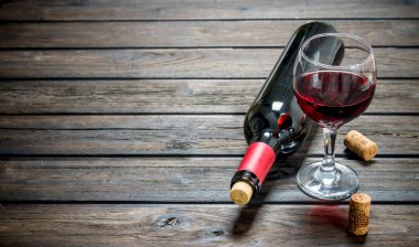 Şarap arka plan. Bir şişeyle kadeh kırmızı şarap. Ahşap bir arka plan üzerinde.