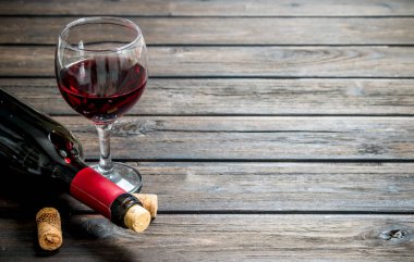 Şarap arka plan. Bir şişeyle kadeh kırmızı şarap. Ahşap bir arka plan üzerinde.