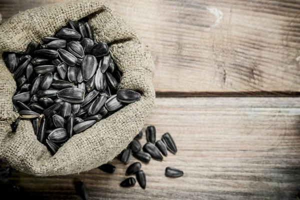 stock image Sunflower seeds in a bag. On a wooden background.