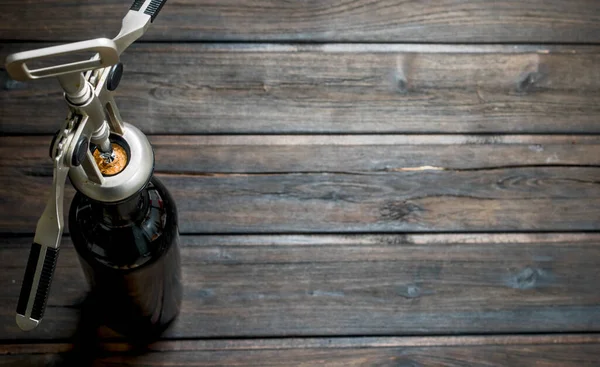 stock image Wine background. A bottle of white wine with a corkscrew. On a wooden background.