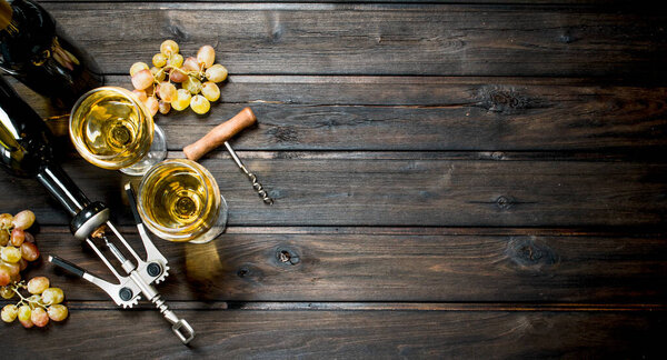 Wine background. White wine with grapes. On a wooden background.