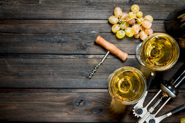 Wine background. White wine with grapes. On a wooden background.