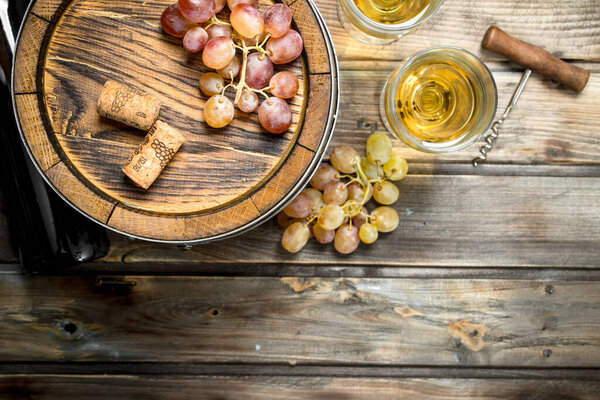 Wine background. White wine in an old barrel. On a wooden background