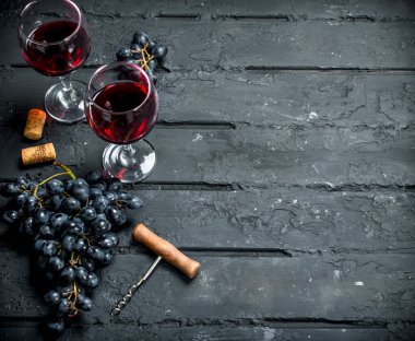 Şarap arka plan. Üzüm ve tirbuşon kırmızı şarap. Siyah bir rustik arka planda.