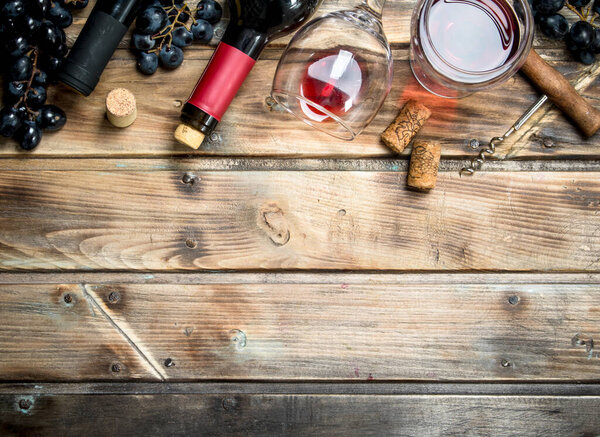 Красное вино в стакане с виноградом и штопором. На деревянном фоне
.