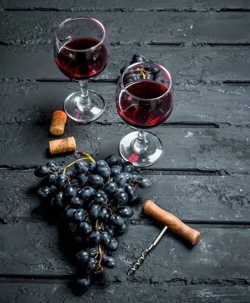 ワインの背景 赤ワインとコルク栓抜きのブドウ 素朴な黒地に — ストック写真