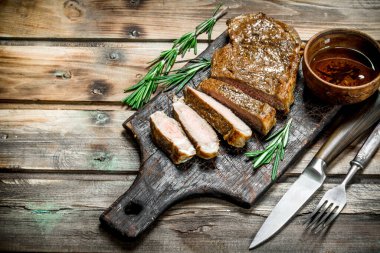 Rosemary ile ızgara sığır eti biftek dilimlenmiş. Ahşap bir arka plan üzerinde.