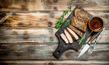 Rosemary ile ızgara sığır eti biftek dilimlenmiş. Ahşap bir arka plan üzerinde.