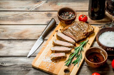 Baharat ve otlar ile ızgara sığır eti biftek. Ahşap bir arka plan üzerinde.