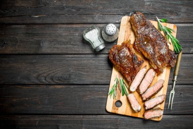 Izgara dana biftek otlar ve baharatlar ile. Ahşap bir masaya.