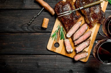 Kırmızı şarap ile ızgara sığır eti biftek. Ahşap bir masaya.