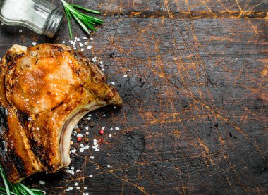 Bir dal taze biberiye ile kemik ızgara domuz biftek. Ahşap bir arka plan üzerinde.