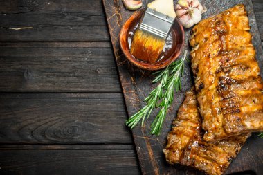 Izgara kaburga sos, otlar ve baharatlar ile. Ahşap bir arka plan üzerinde.