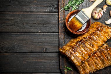 Izgara kaburga sos, otlar ve baharatlar ile. Ahşap bir arka plan üzerinde.