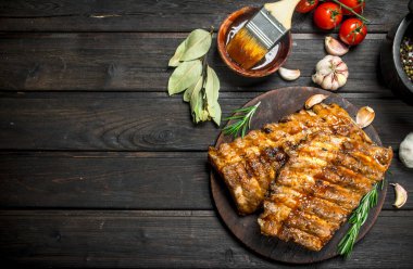 Izgara kaburga sos, otlar ve baharatlar ile. Ahşap bir arka plan üzerinde.