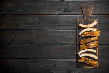 Eski bir tahtada dilimlenmiş ızgara kaburgalar. Ahşap bir arka plan üzerinde.