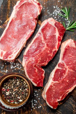 Rosemary ile ham mermer sığır biftek. Ahşap bir arka plan üzerinde.