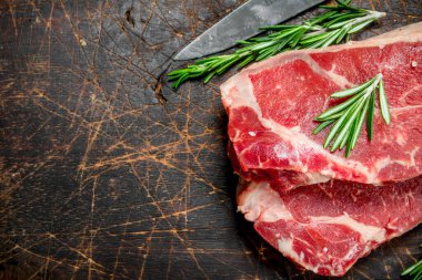 Rosemary ile ham mermer sığır biftek. Ahşap bir arka plan üzerinde.