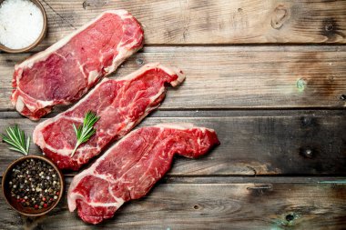 Ham mermer sığır biftek tuz ve Aromatik baharatlar ile. Ahşap bir arka plan üzerinde.