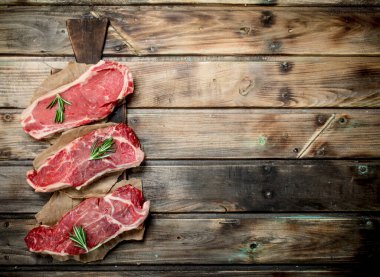 Rosemary ile ham mermer sığır biftek. Ahşap bir arka plan üzerinde.