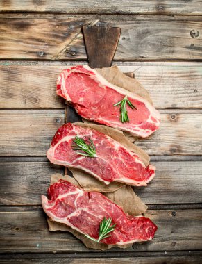 Rosemary ile ham mermer sığır biftek. Ahşap bir arka plan üzerinde.