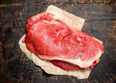 Kağıt üzerinde sulu sığır eti çiğ biftek. Ahşap bir arka plan üzerinde.