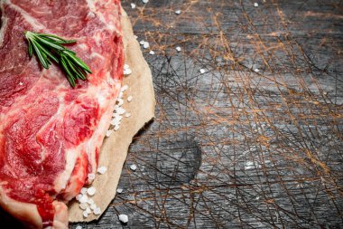 Çiğ biftek güzel kokulu biberiye dalı ile sulu biftek. Ahşap bir arka plan üzerinde.