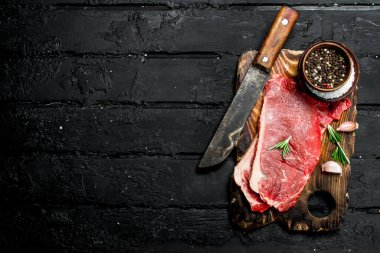Baharatlar ve tuz ile ham sığır eti biftek. Siyah bir rustik arka planda.