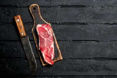 Çiğ biftek. Siyah rustik arka planda.