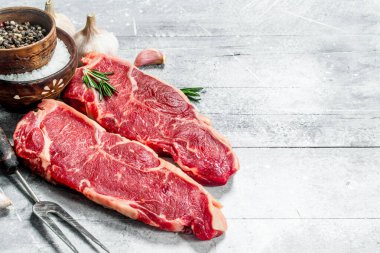 Ham sığır eti biftek baharat ve otlar ile. Rustik bir arka plan üzerinde.