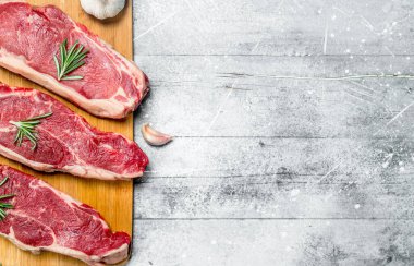 Ham sığır eti biftek baharat ve otlar ile. Rustik bir arka plan üzerinde.