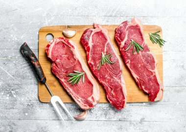 Ham sığır eti biftek baharat ve otlar ile. Rustik bir arka plan üzerinde.