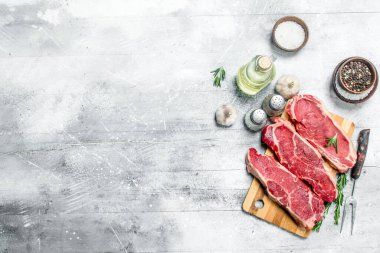Ham sığır eti biftek baharat ve otlar ile. Rustik bir arka plan üzerinde.