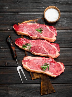 Ham sığır eti biftek tuz ve baharatlar ile. Ahşap bir arka plan üzerinde.