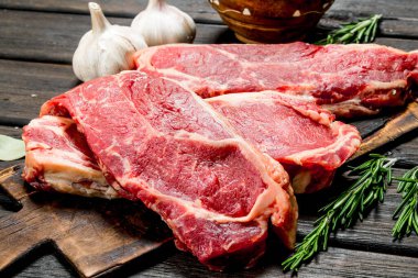 Ham sığır eti biftek tuz ve baharatlar ile. Ahşap bir arka plan üzerinde.