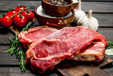 Ham sığır eti biftek tuz ve baharatlar ile. Ahşap bir arka plan üzerinde.