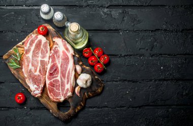 Çiğ domuz biftek aromatik ve otlar ve baharatlar ile. Siyah bir rustik arka planda.