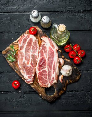 Çiğ domuz biftek aromatik ve otlar ve baharatlar ile. Siyah bir rustik arka planda.