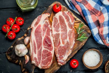 Çiğ domuz biftek aromatik ve otlar ve baharatlar ile. Siyah bir rustik arka planda.