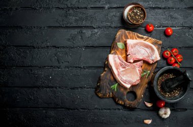 Baharat ile kemikte çiğ domuz biftek. Siyah bir rustik arka planda.