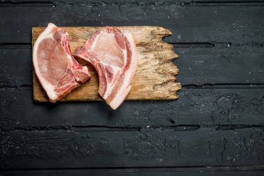 Kemik üzerinde çiğ domuz biftek. Siyah bir rustik arka planda.