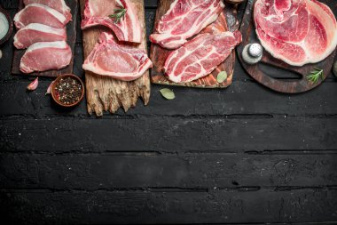 Domuz eti ile baharat çeşitleri. Siyah bir rustik arka planda.