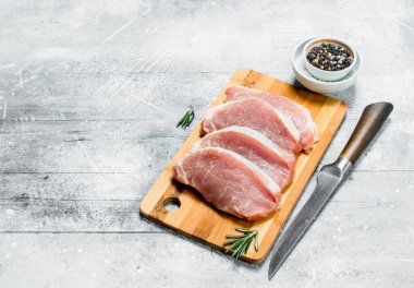 Çiğ domuz biftek bıçağı ve baharatlar ile. Rustik bir arka plan üzerinde.