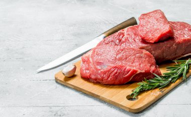 Çiğ et. Biberiye dalları ile taze et parçaları. Rustik bir arka plan üzerinde